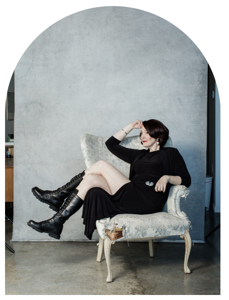 Heidi Waterman seated in an armchair in front of an arched studio backdrop